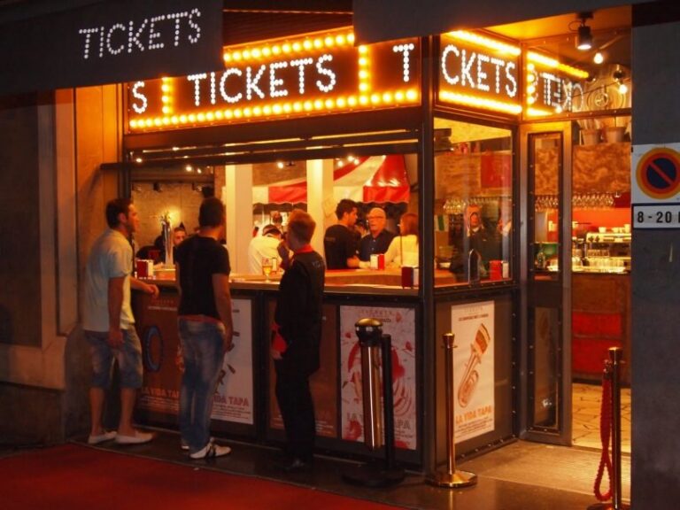 Fachada nocturna de Tickets en la Avinguda del Paral·lel, con marquesina de bombillas y letras de feria imitando un cine antiguo